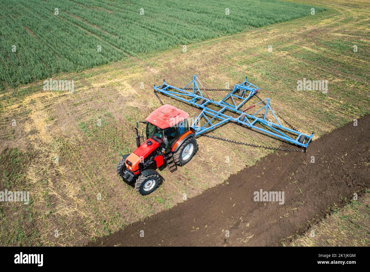 A large agricultural machine cultivates the land. The view from the top. Plowing land for planting crops. photos from the bird's eye view with a quadc Stock Photo