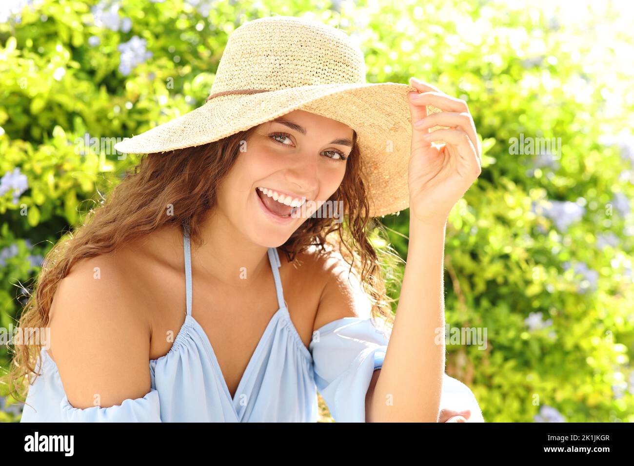 Happy woman with pamela hat looks at you in a green garden Stock Photo