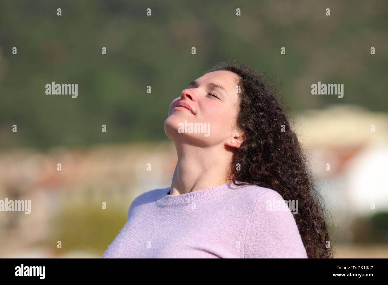 Woman with curly hair breathing fresh air in a town Stock Photo