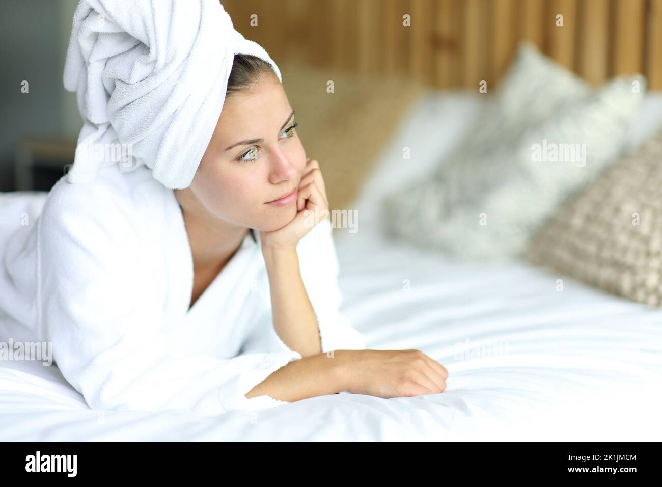 Pensive woman after showering contemplating lying on the bed at home Stock Photo