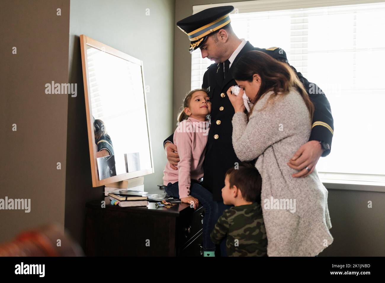 Family saying goodbye to father in military dress uniform in bedroom Stock Photo