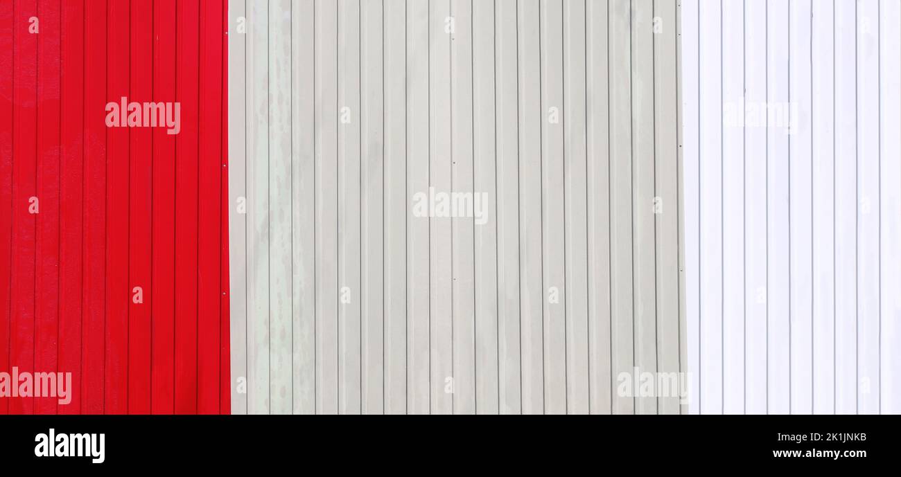 Wave Sheets fence of red, beige and white colors. Horizontal background with galvanized iron sheets of different color. Colored corrugated metal roofi Stock Photo