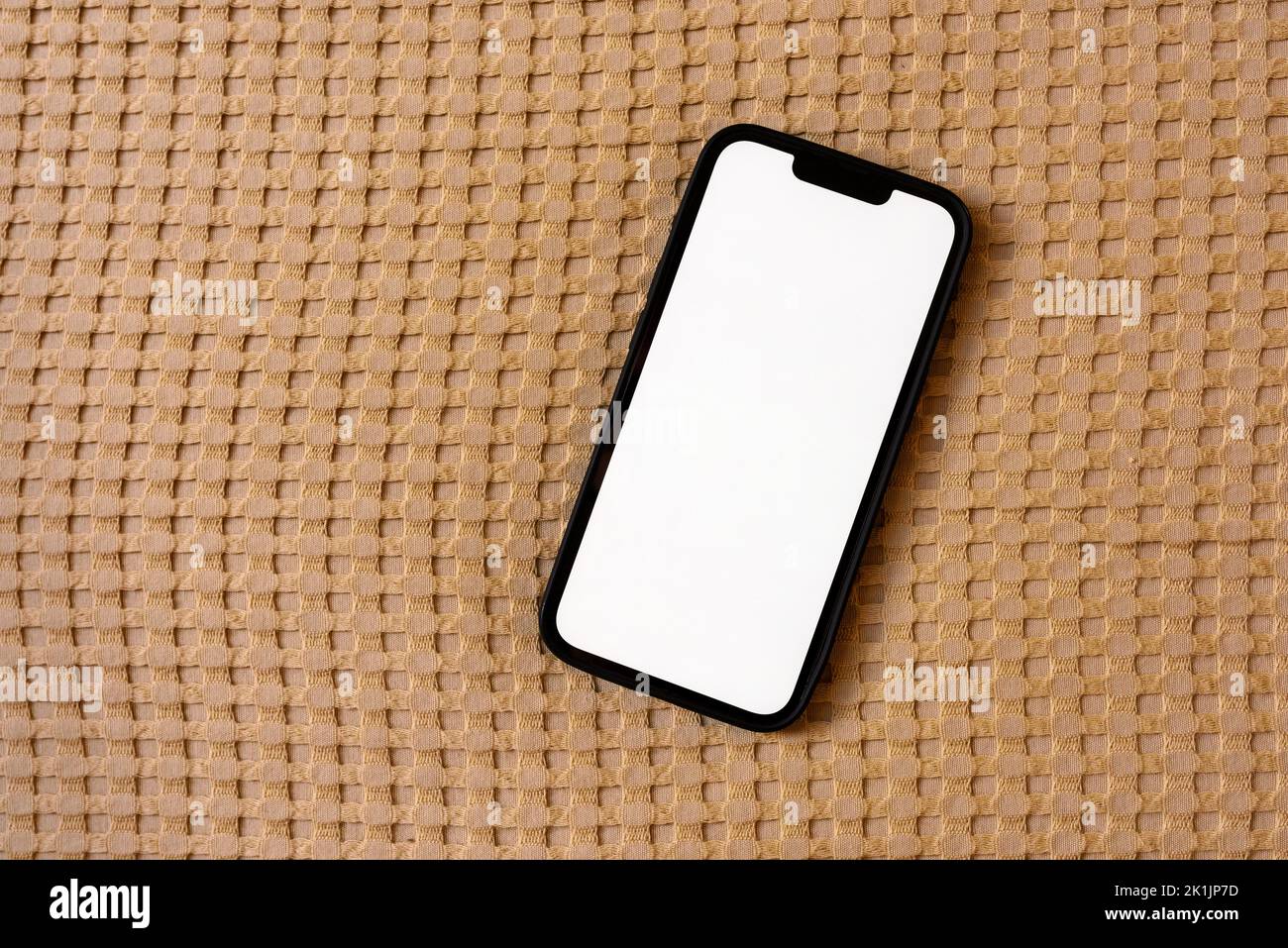Top down mockup image of smartphone with blank white touch screen on bed linen Stock Photo