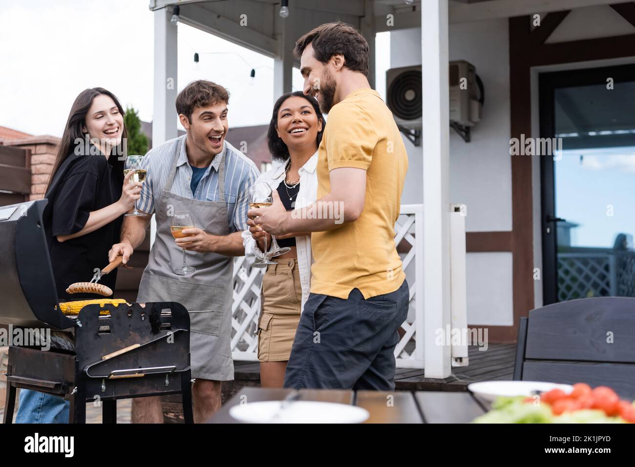 Cheerful interracial friends preparing food for bbq during party on backyard Stock Photo