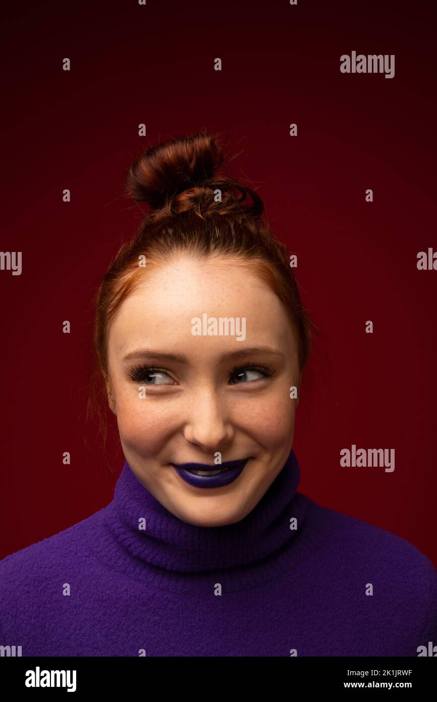 Portrait of smiling redhead teenage girl with purple turtleneck Stock Photo
