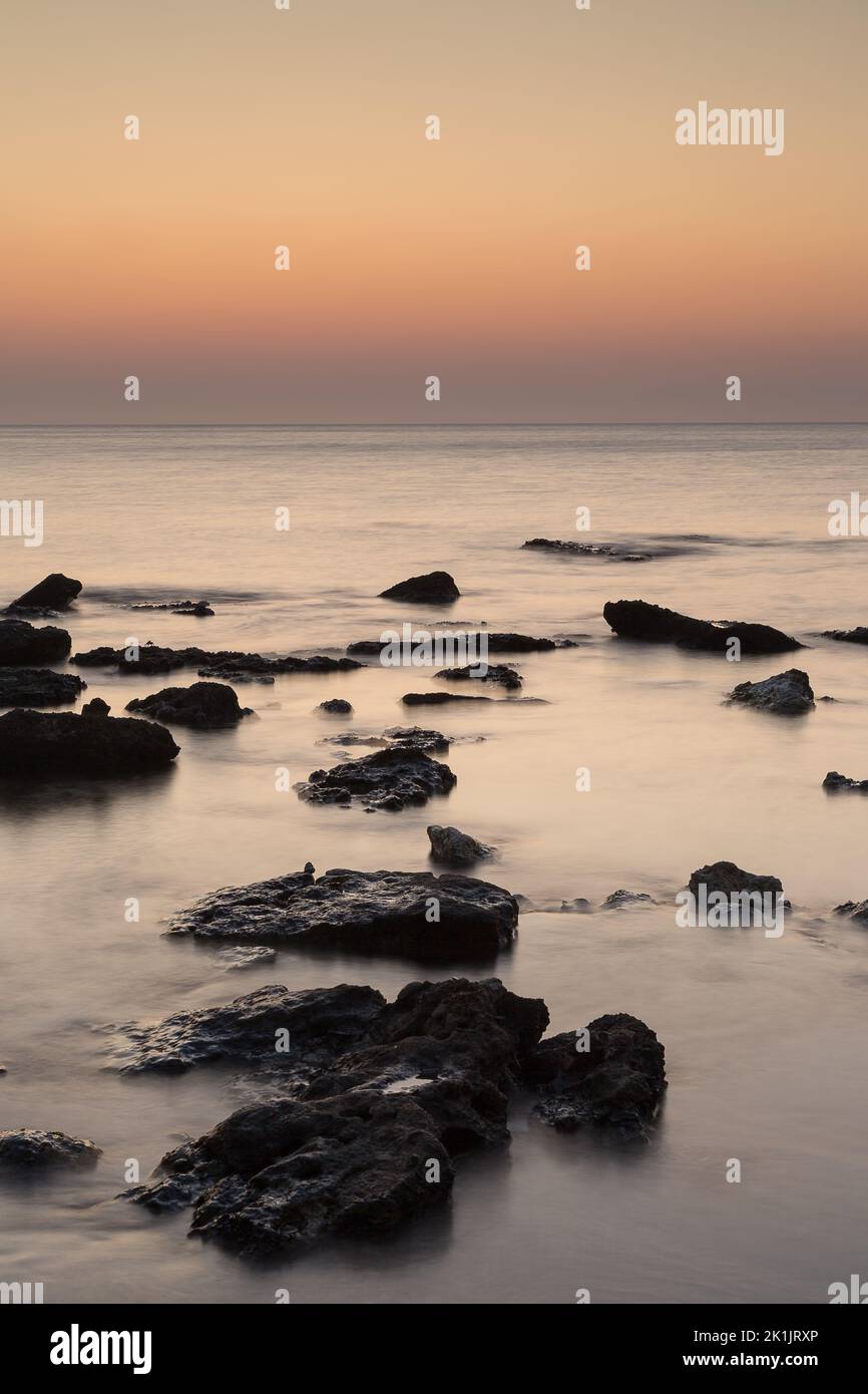 Rocks in Ocean in Faliraki, Rhodes, Greece at sunrise. Stock Photo