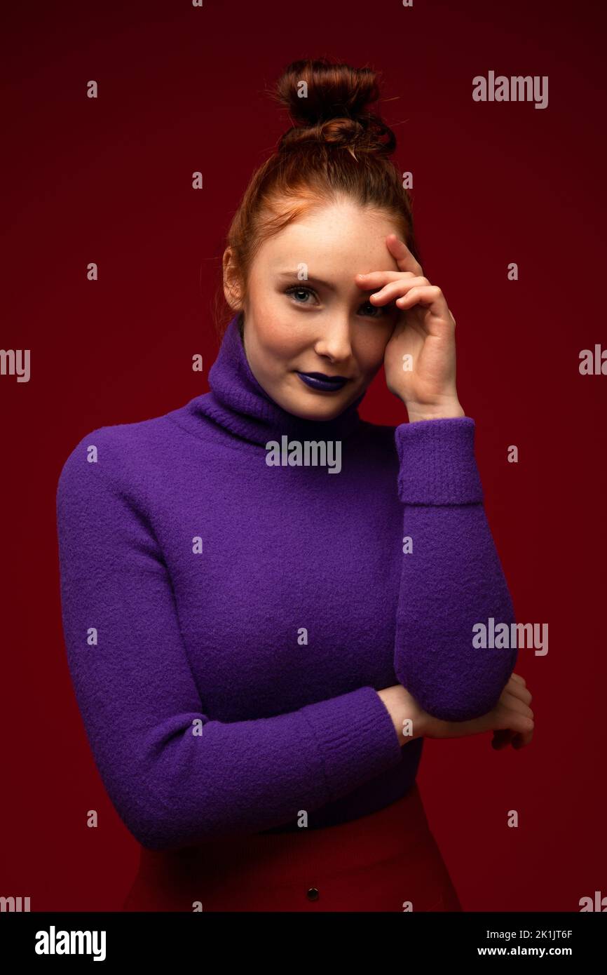 Portrait of confident redhead teenage girl in purple turtleneck Stock Photo