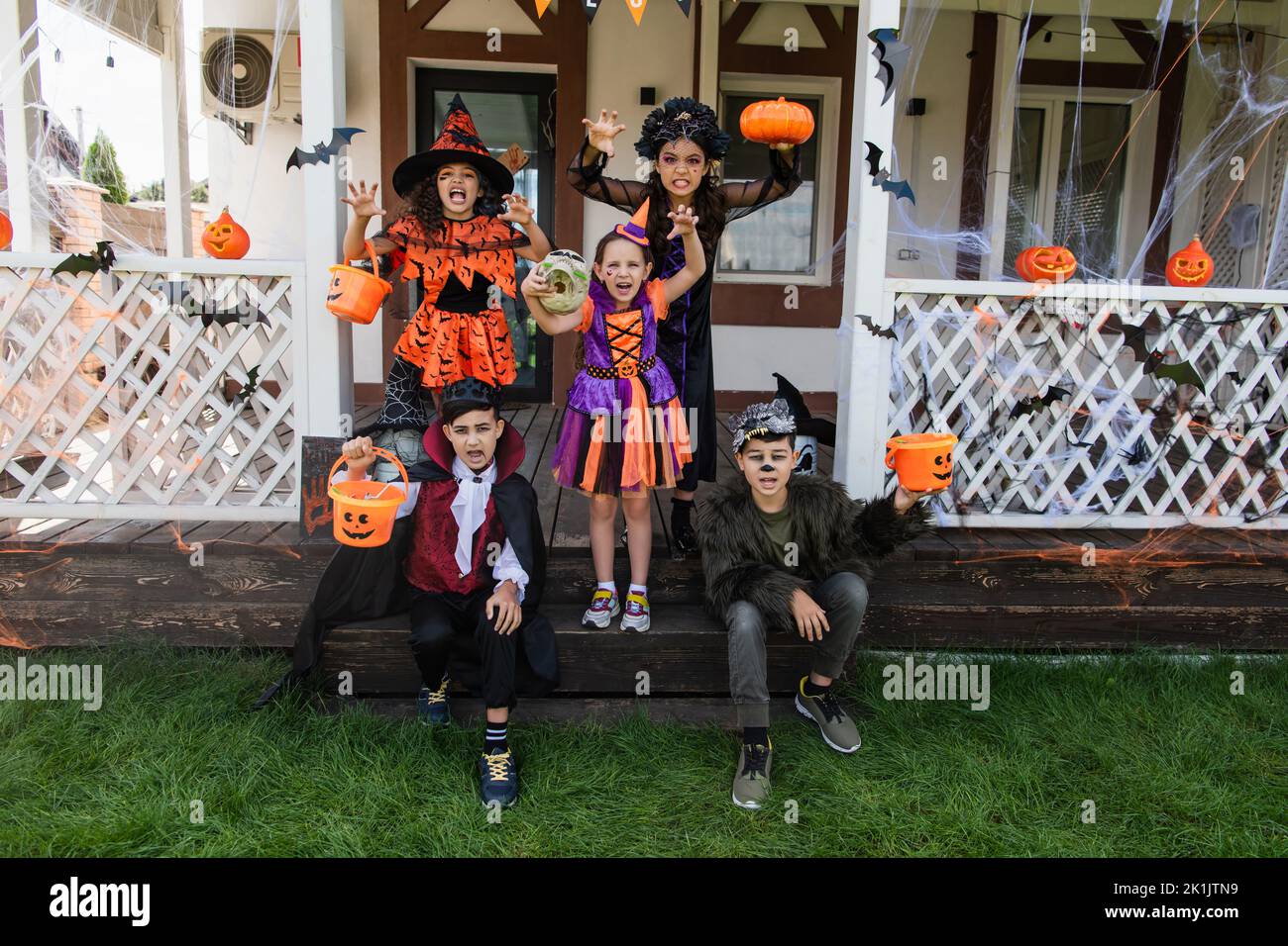 multiethnic kids in halloween costumes grimacing and showing scary