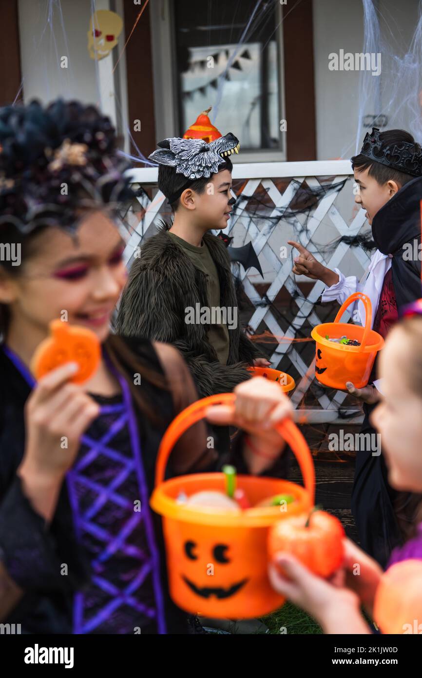 Asian boy in halloween costume holding bucket and pointing with finger ...