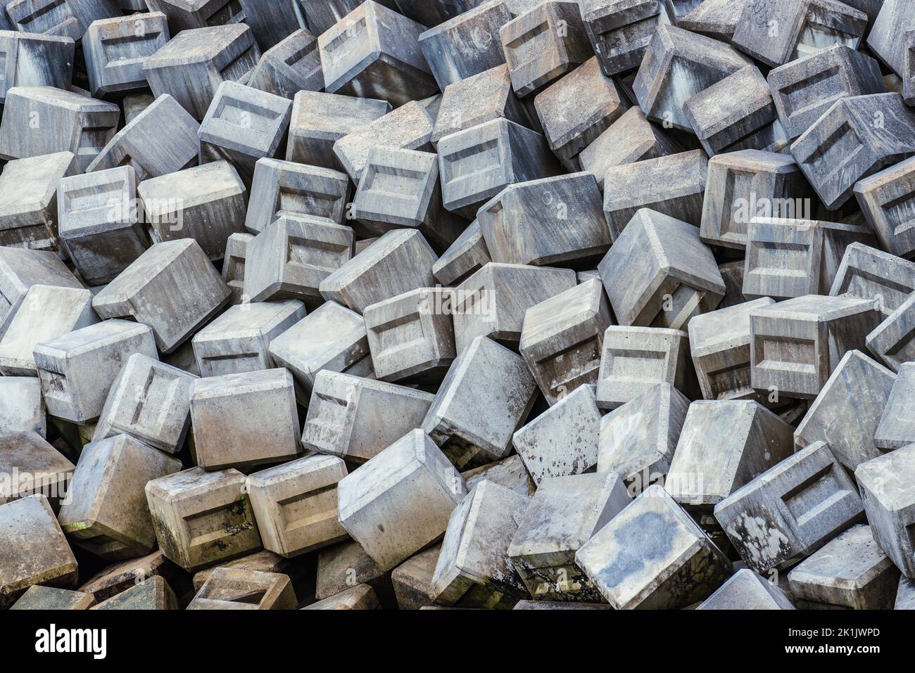 Concrete blocks piled form a breakwater and cover the entire frame Stock Photo