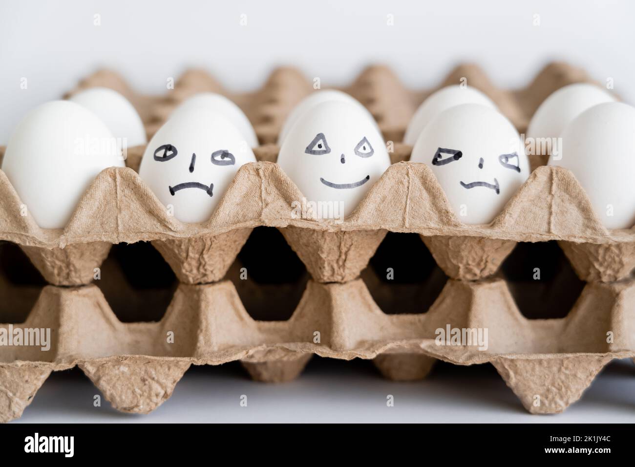 Painted eggs with different facial expressions in carton boxes on white background Stock Photo