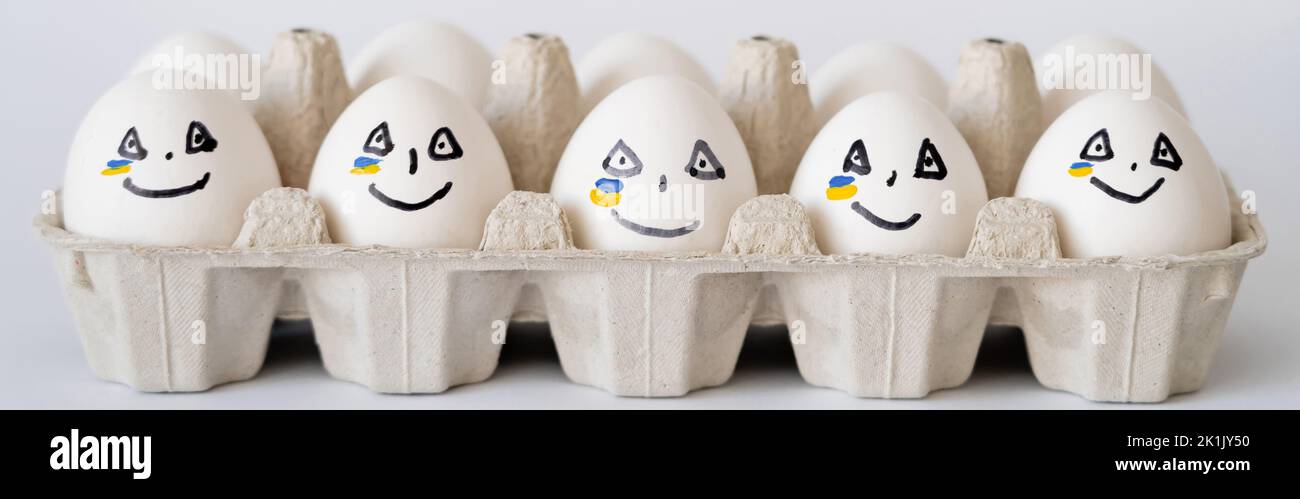 Painted eggs with facial expression and ukrainian flag in container on white background, banner Stock Photo