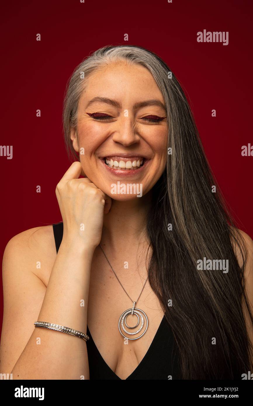 Portrait of happy woman with long gray hair and red eyeliner Stock Photo