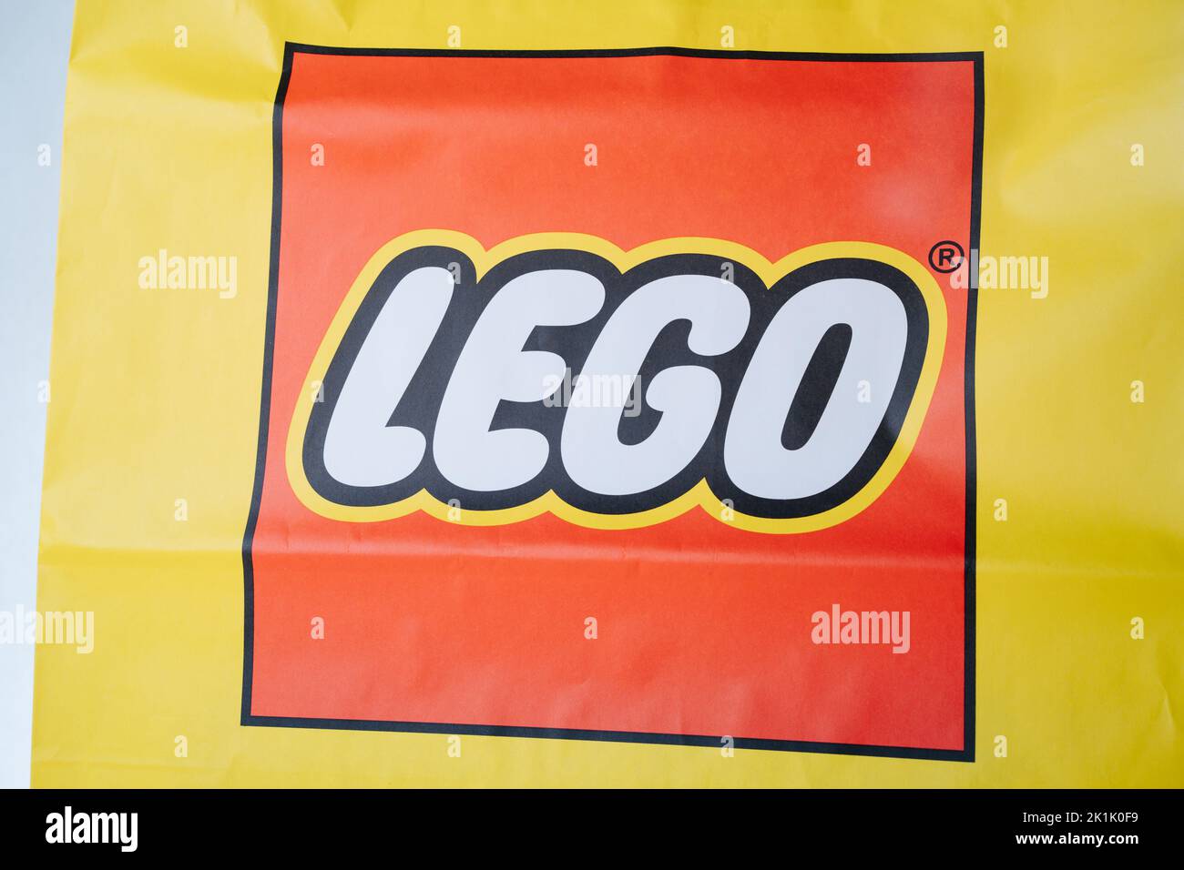Square red lego logo on a yellow paper bag close up. Stock Photo