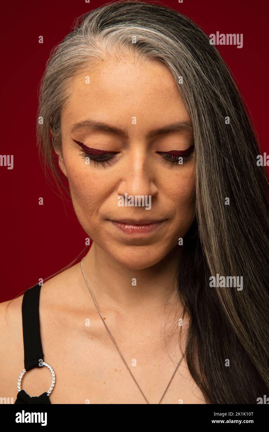 Portrait of serene woman with long gray hair and red eyeliner Stock Photo