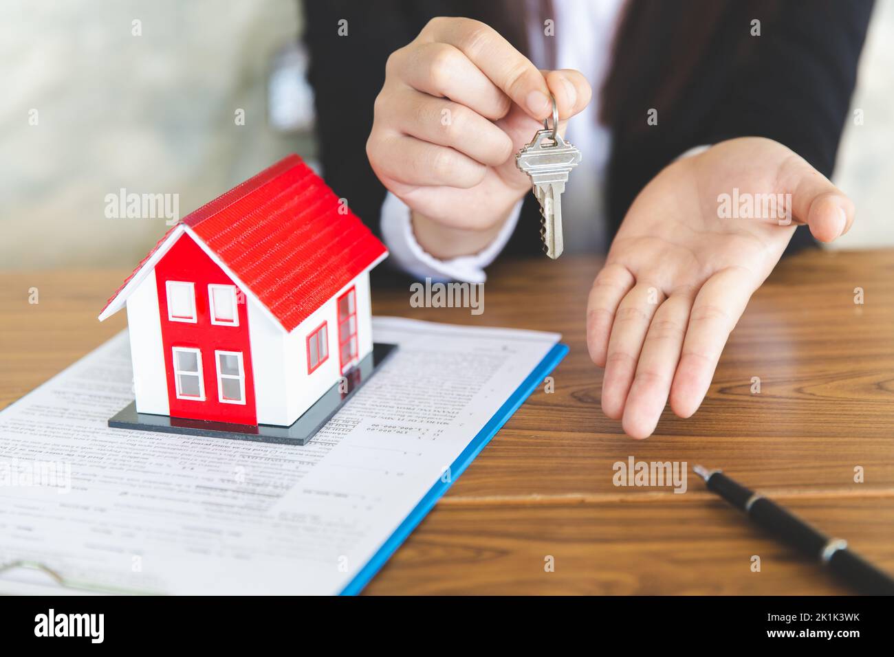 Your new house, real estate agent holding house key to his client after signing contract agreement in office,concept for real estate, renting property Stock Photo