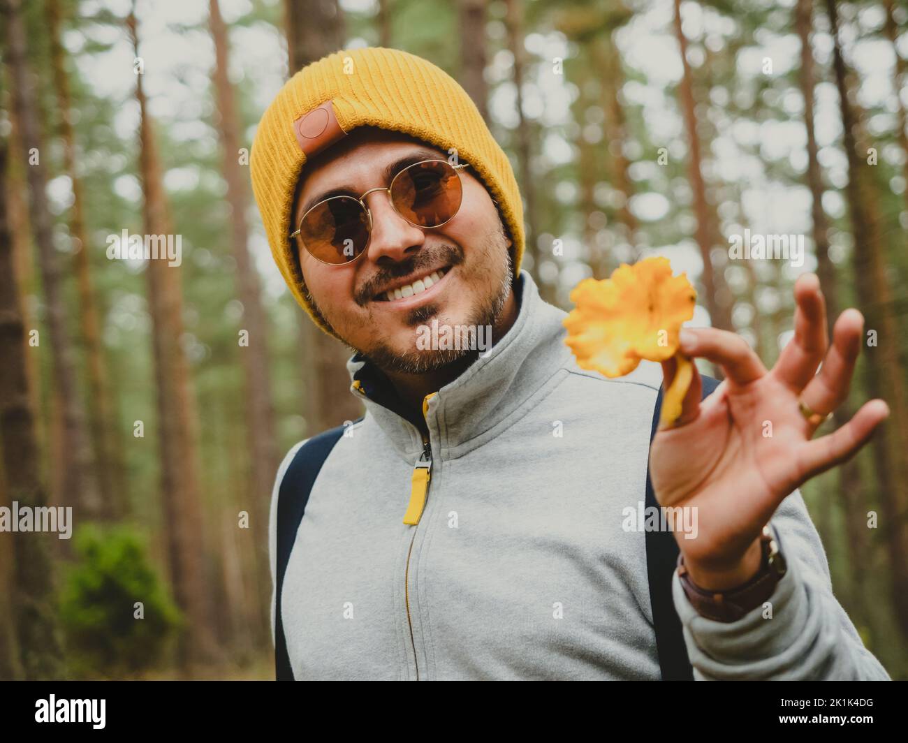 smiling handsome young man finds mushroom in deep pine forest in autumn Stock Photo