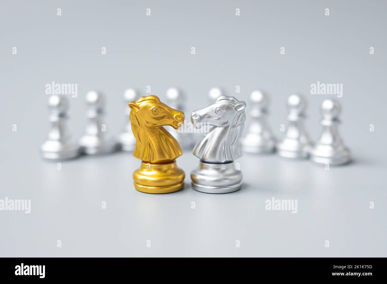 The gold horse, knight chess piece standing with falling silver pawn chess  pieces on chessboard on white background with copy space. Leadership,  winner, competition, and business strategy concept. Photos