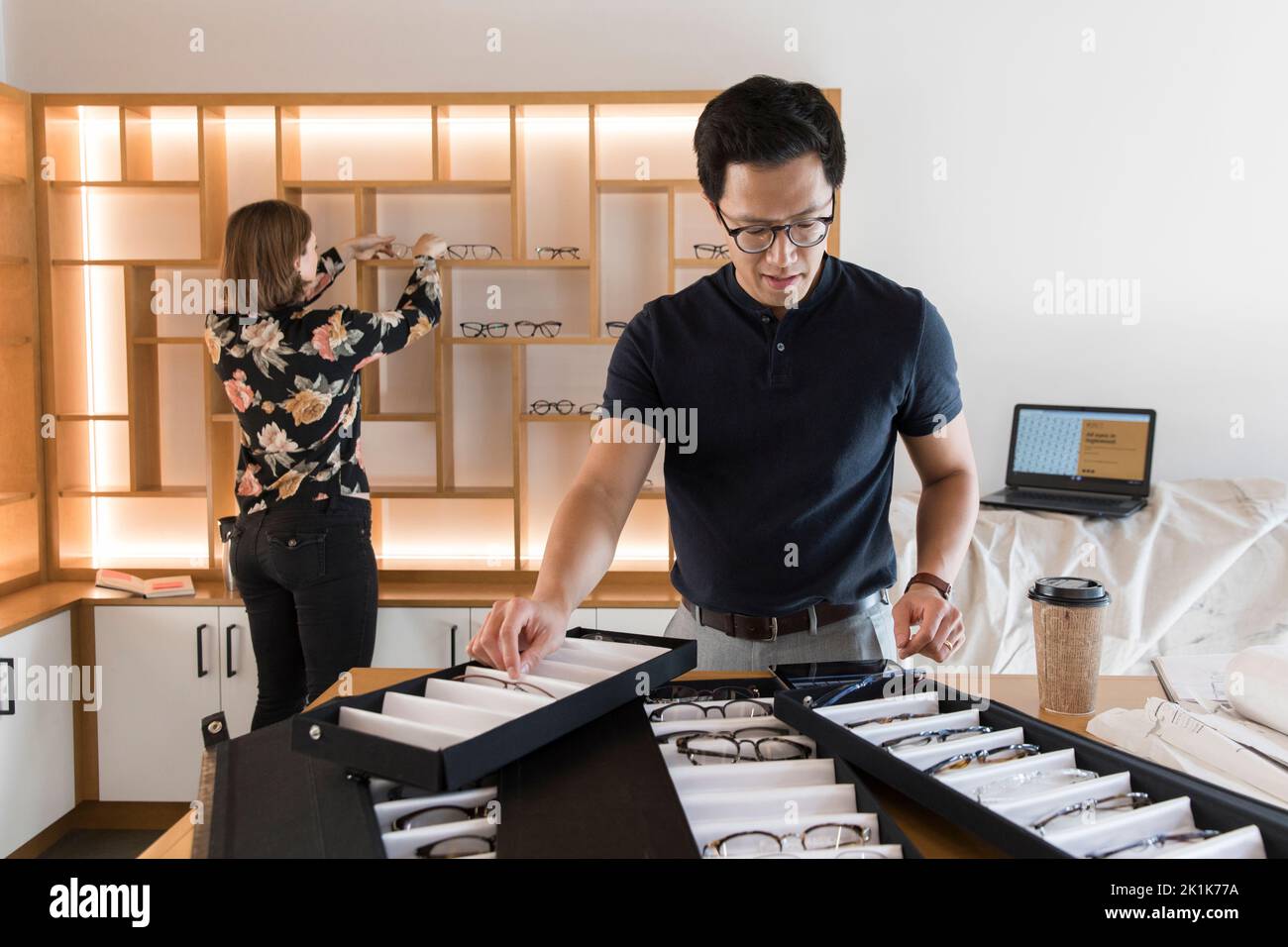 Optometry shop owners arranging eyeglasses on display, preparing for shop opening Stock Photo