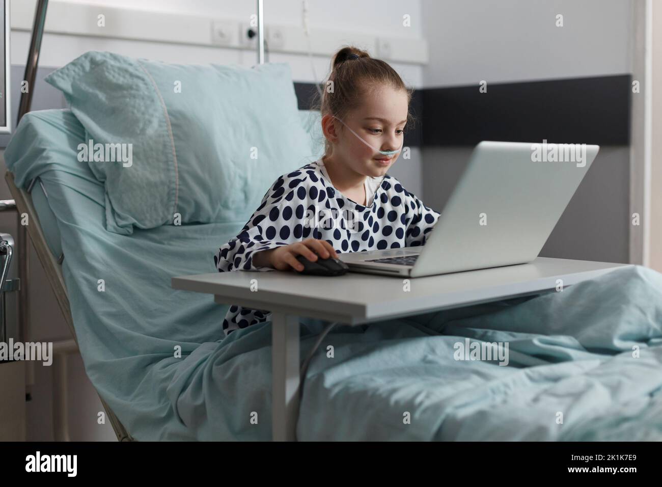 Sick little girl playing games on laptop while hospitalized in