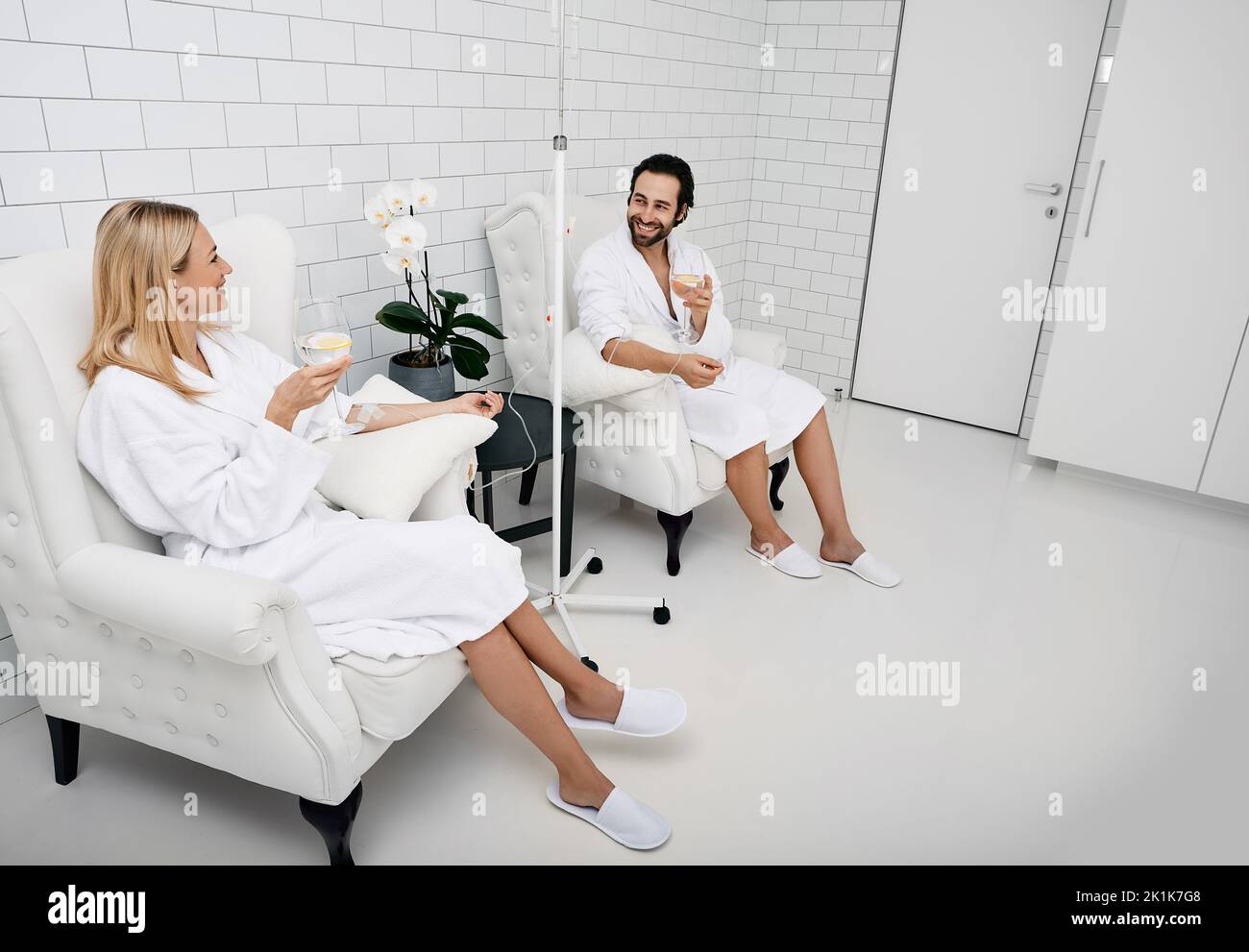 Handsome man with his girlfriend with glasses of refreshing lemon drink in wellness center. Couple while intravenous vitamin therapy. Detox human orga Stock Photo