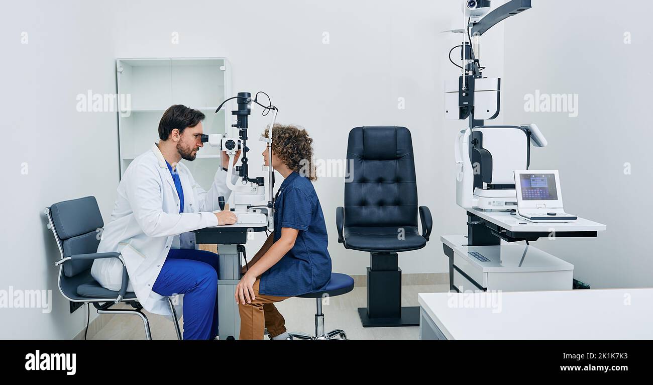 Pediatric ophthalmology. Optometrist checking eyesight of boy patient at modern eye clinic Stock Photo