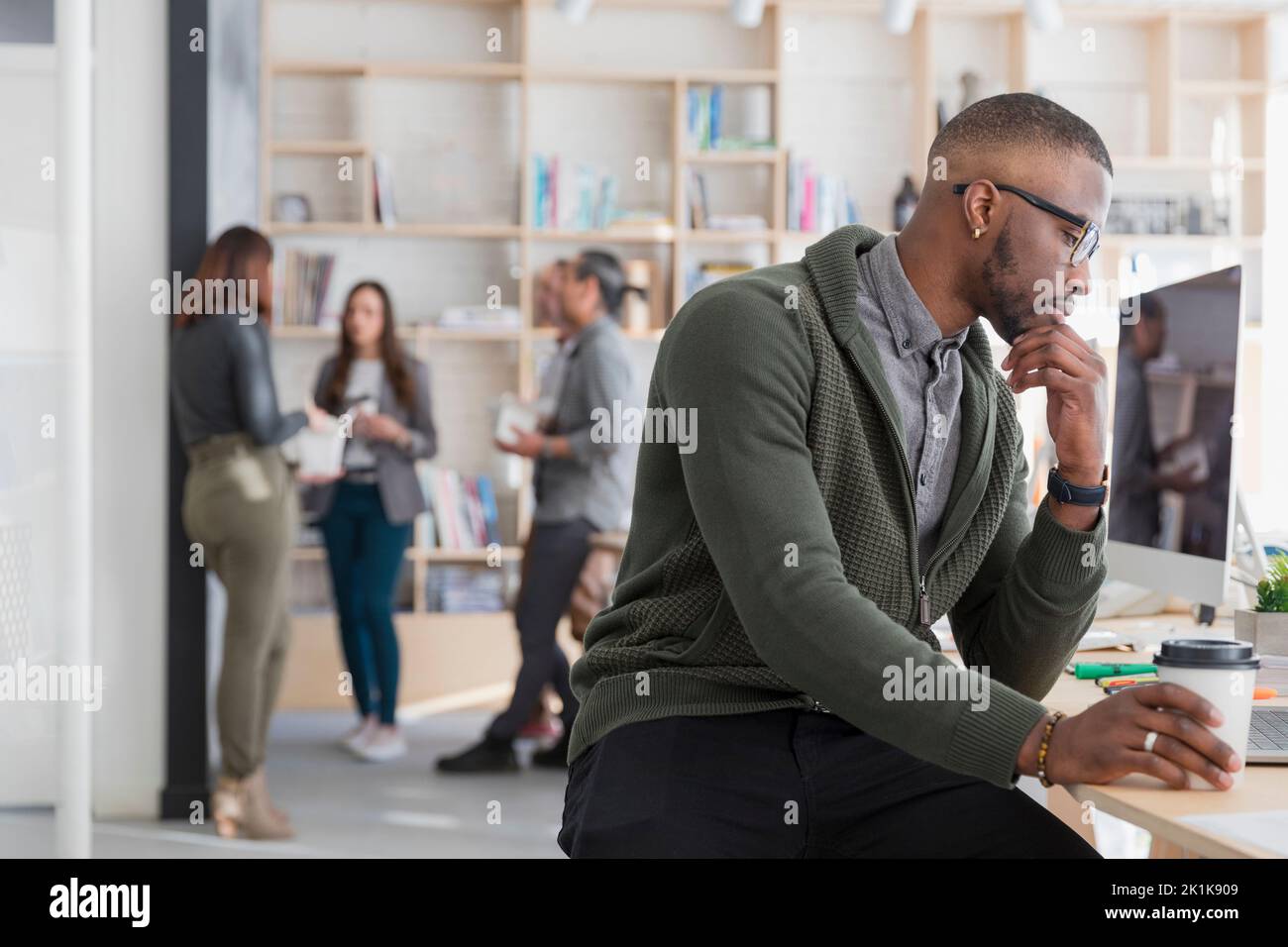 Creative professional at desk with hand on chin Stock Photo