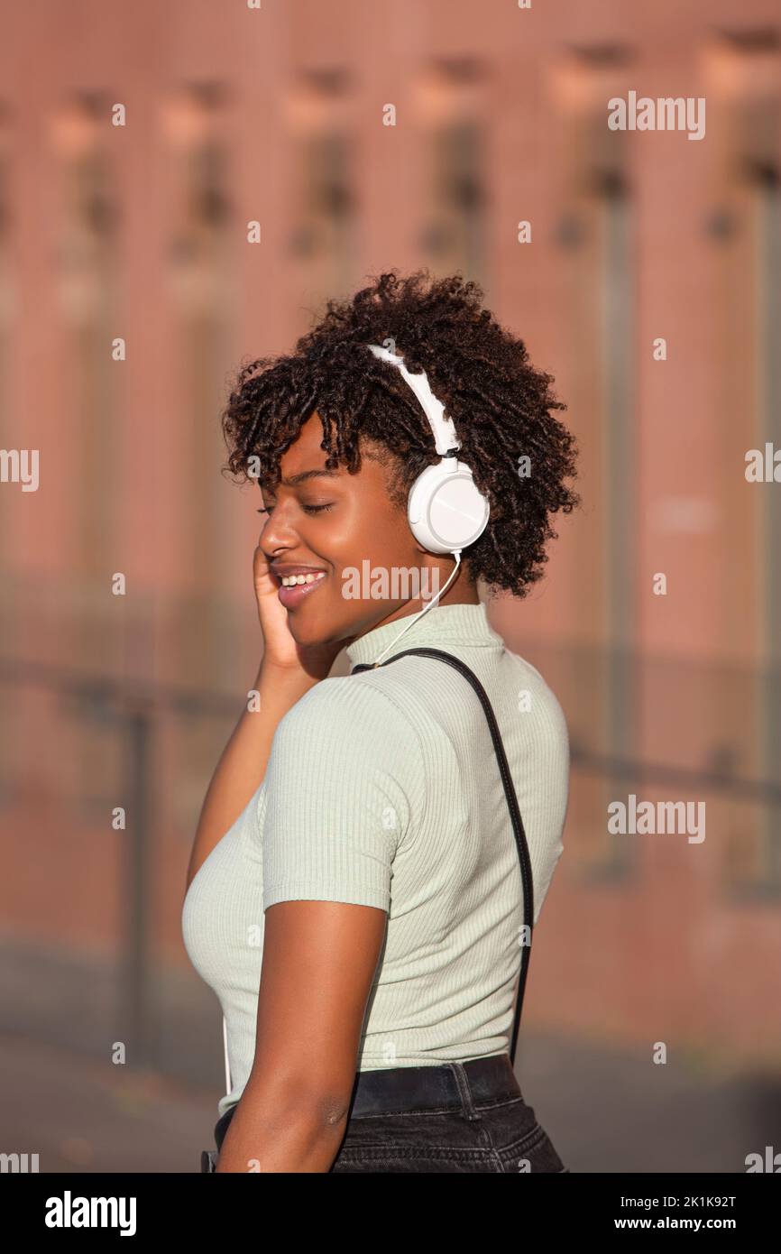 Latin American teenage girl with curly hair listening to music on ...