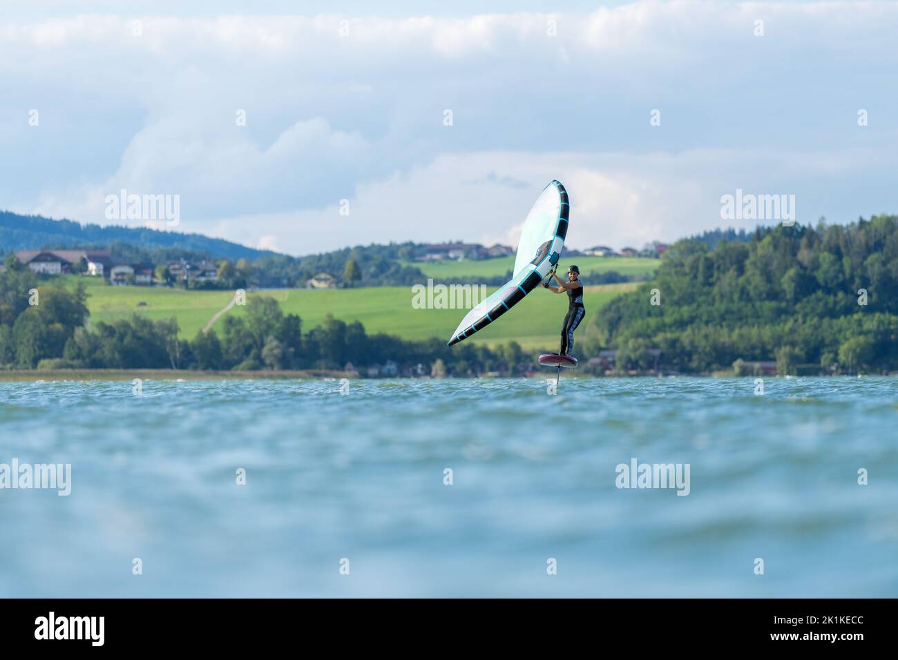 Woman wing foiling on lake Wallersee, Salzburg, Austria Stock Photo