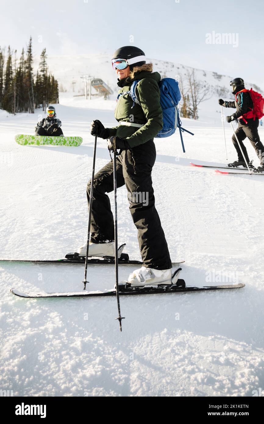 Female skier with backpack skiing on snowy mountain ski slope Stock