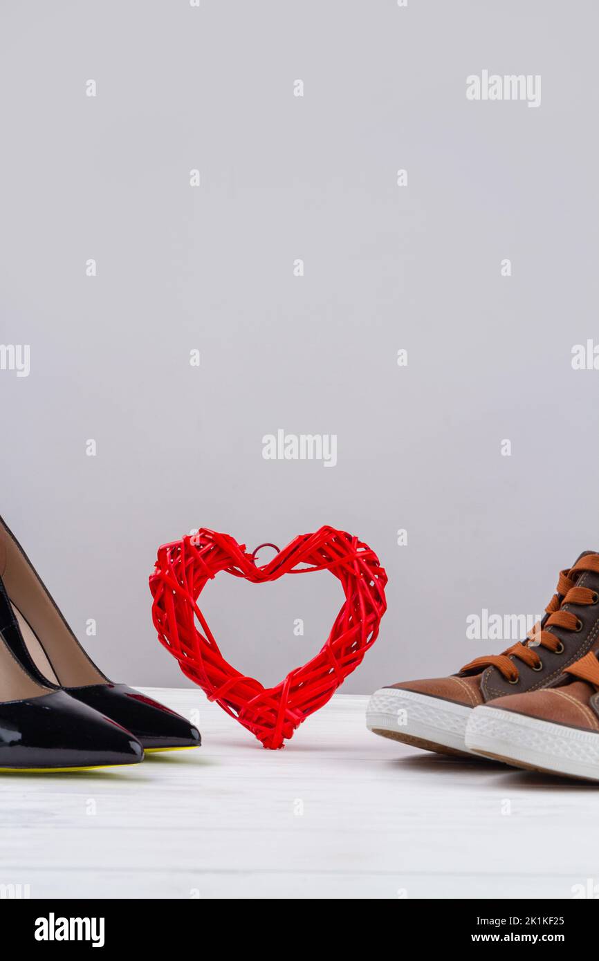 Still life of mens and womens shoes and red heart. Vertical shot copy space. Stock Photo