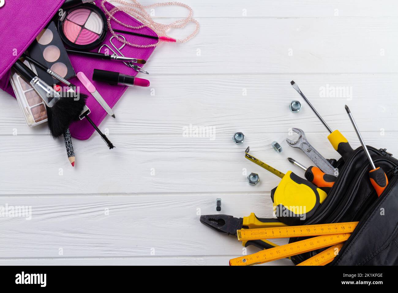 Flat lay repair tools and make-up accessories. Concept of man versus woman. Space for text on white wooden desk. Stock Photo
