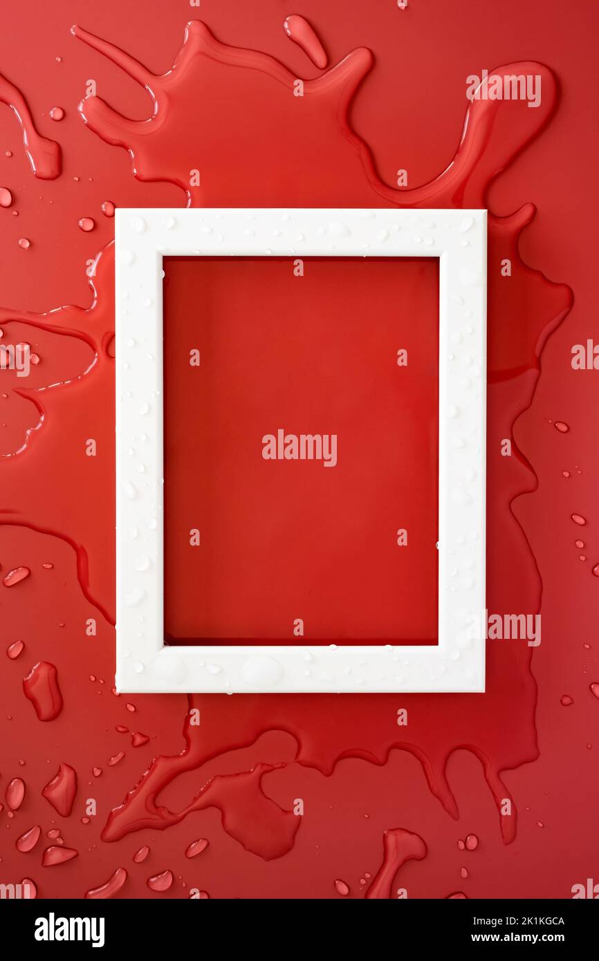 White rectangular empty frame on clean spilled water, on a red background. Copy space. Flat lay. Top view.  Stock Photo