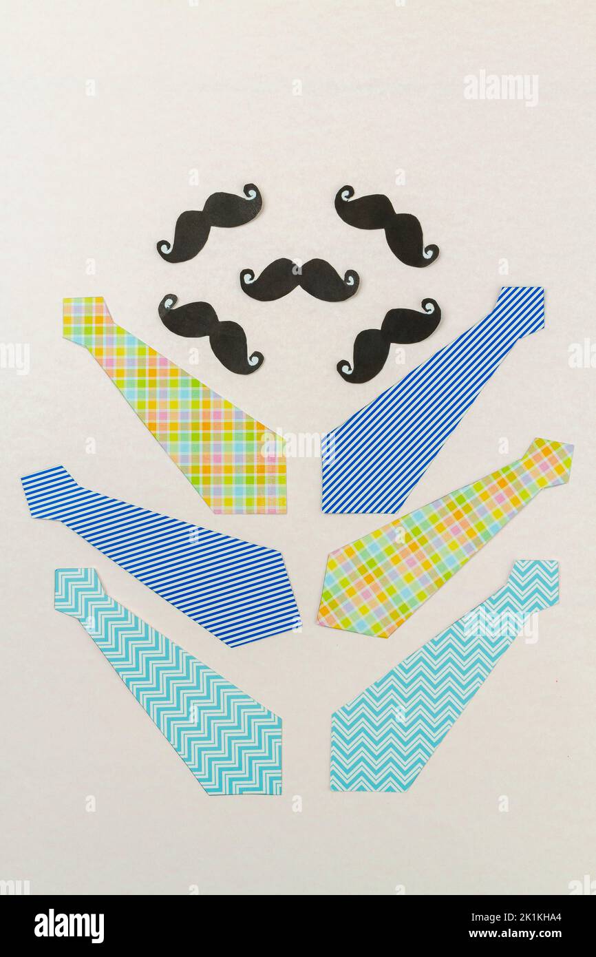 Arrangement of neckties and moustaches on white surface. Fathers day concept. Stock Photo