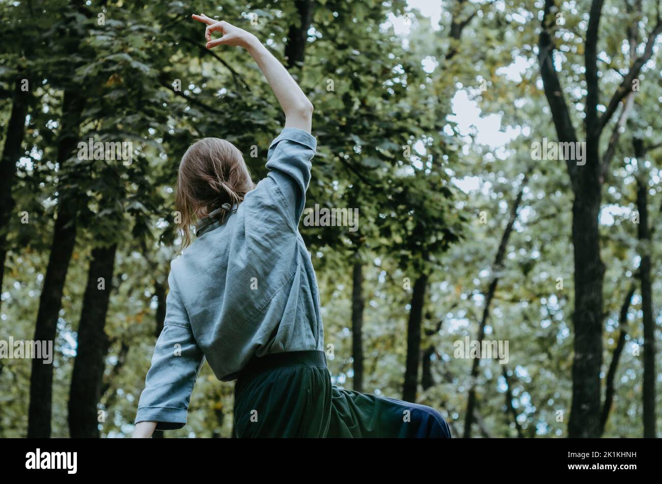 Woman doing yoga peaceful warrior pose in early autumn forest Stock Photo