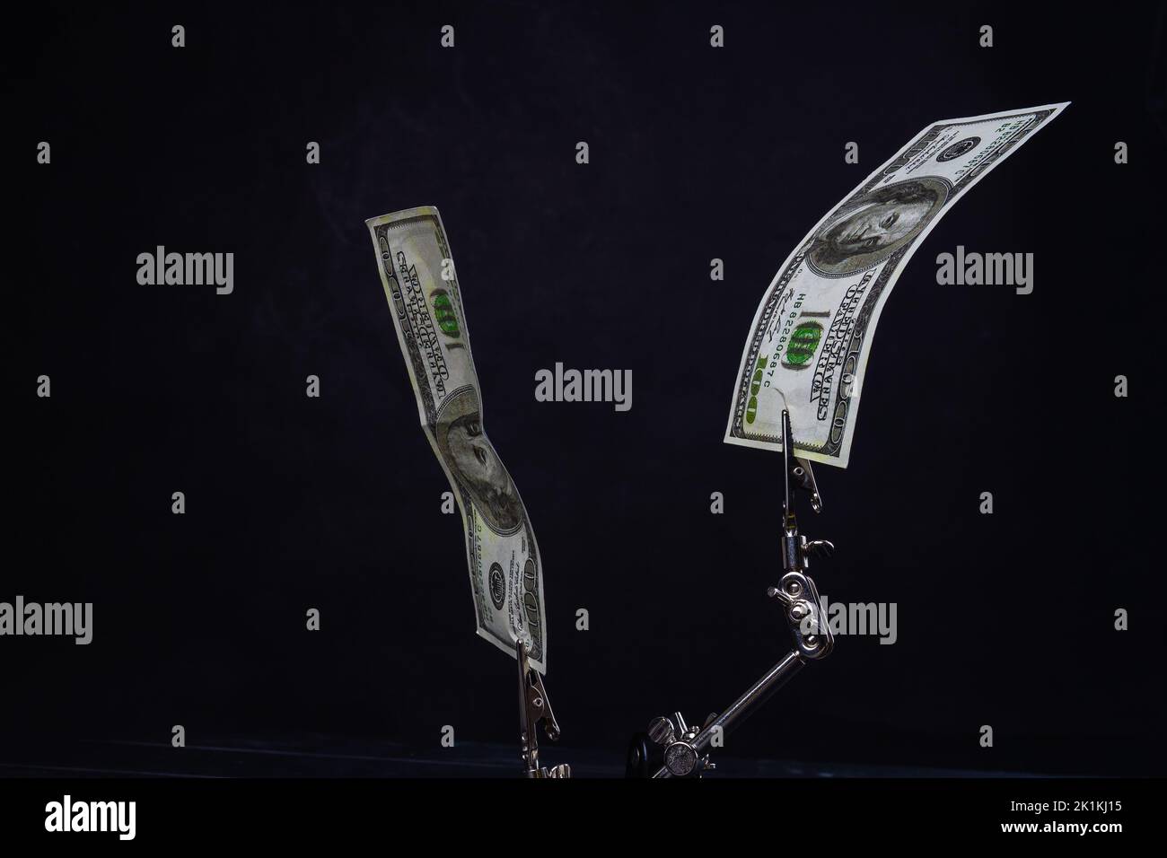 Close up metallic holders with hundred dollars. Isolated on black background. Stock Photo