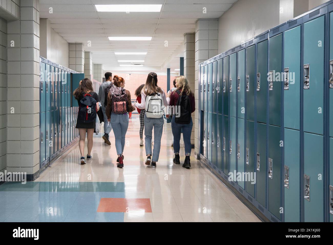 High school students with backpacks walking past lockers in corridor Stock Photo Alamy