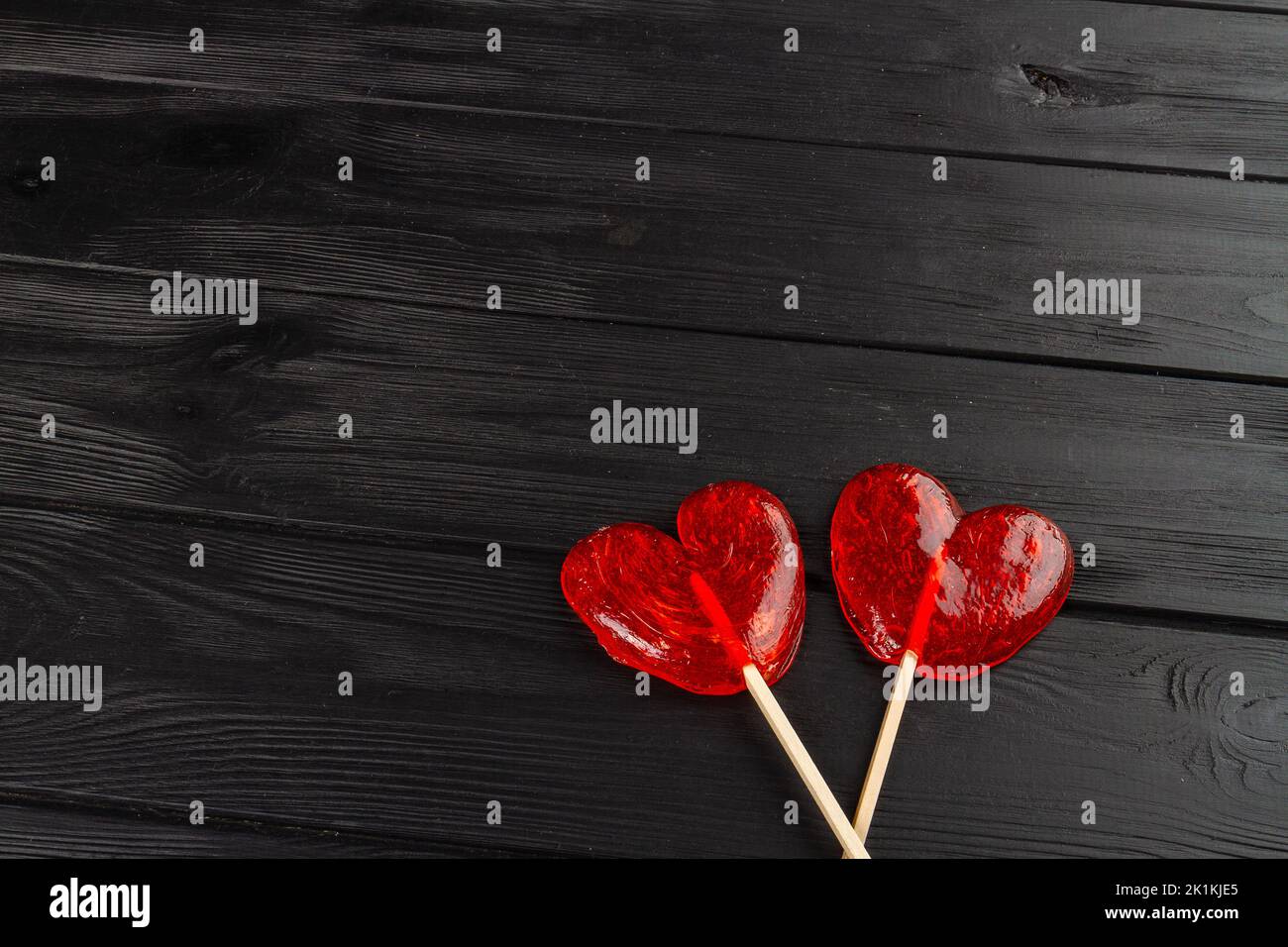 Two red heart lollipops on black wooden desk. Love and valentines day concept. Stock Photo