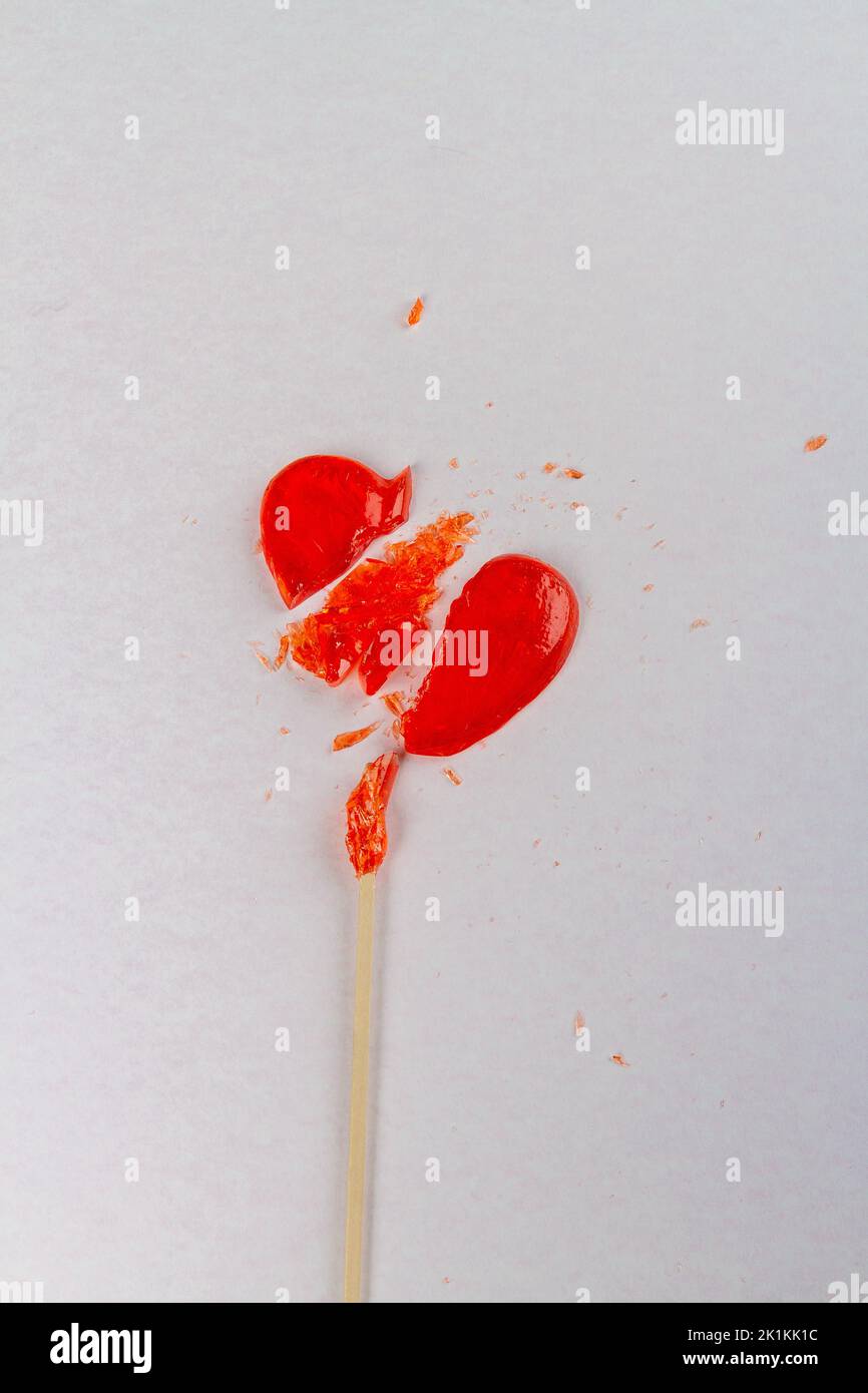 Vertical shot of broken heart shaped lollipop. Unrequited love concept. Stock Photo