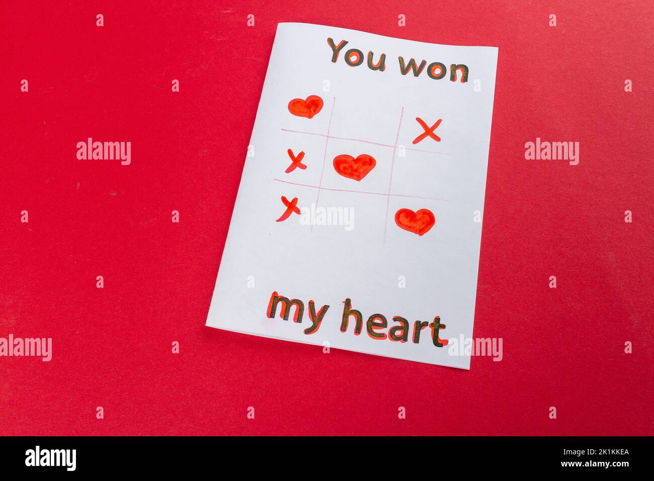Paper with you won my heart inscription. Tic tac toe. Romantic love declaration on red background. Stock Photo