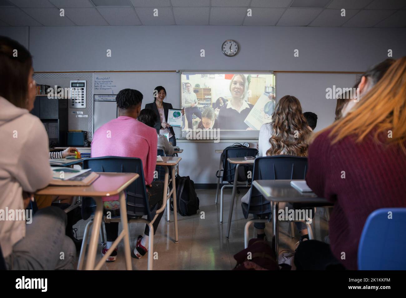 High school students watching video on projection screen in classroom