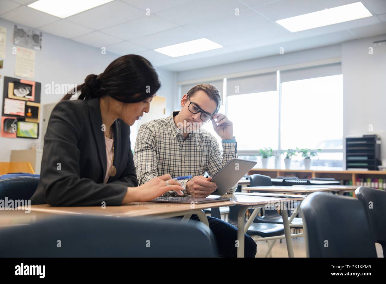 High school teachers with digital tablets talking in classroom Stock