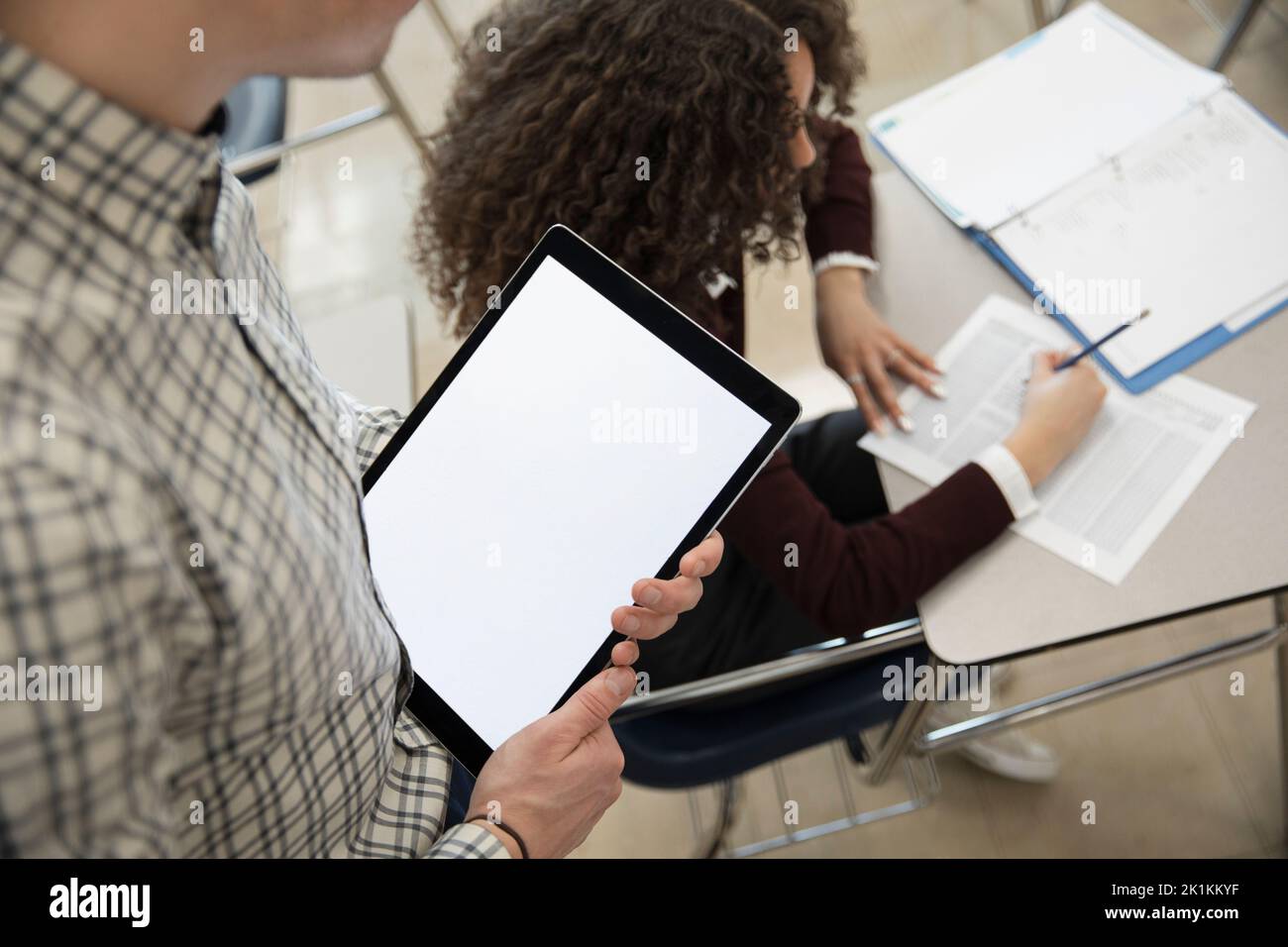 High school geography teacher with digital tablet helping student Stock