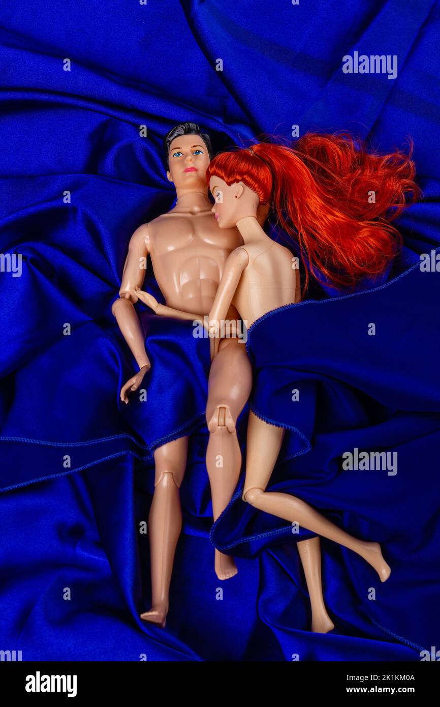 Lying naked doll couple on blue clothing. Vertical shot top view. Stock Photo