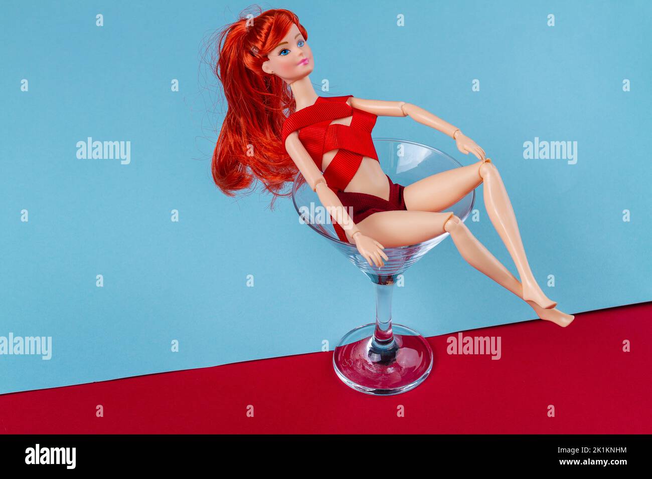 Sexy ginger doll bathing in martini glass. mannequin wrapped in red tape. Stock Photo