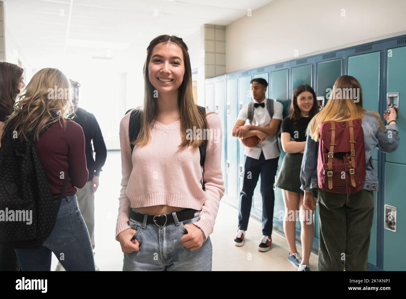 Portrait confident smiling high school girl at lockers in corridor