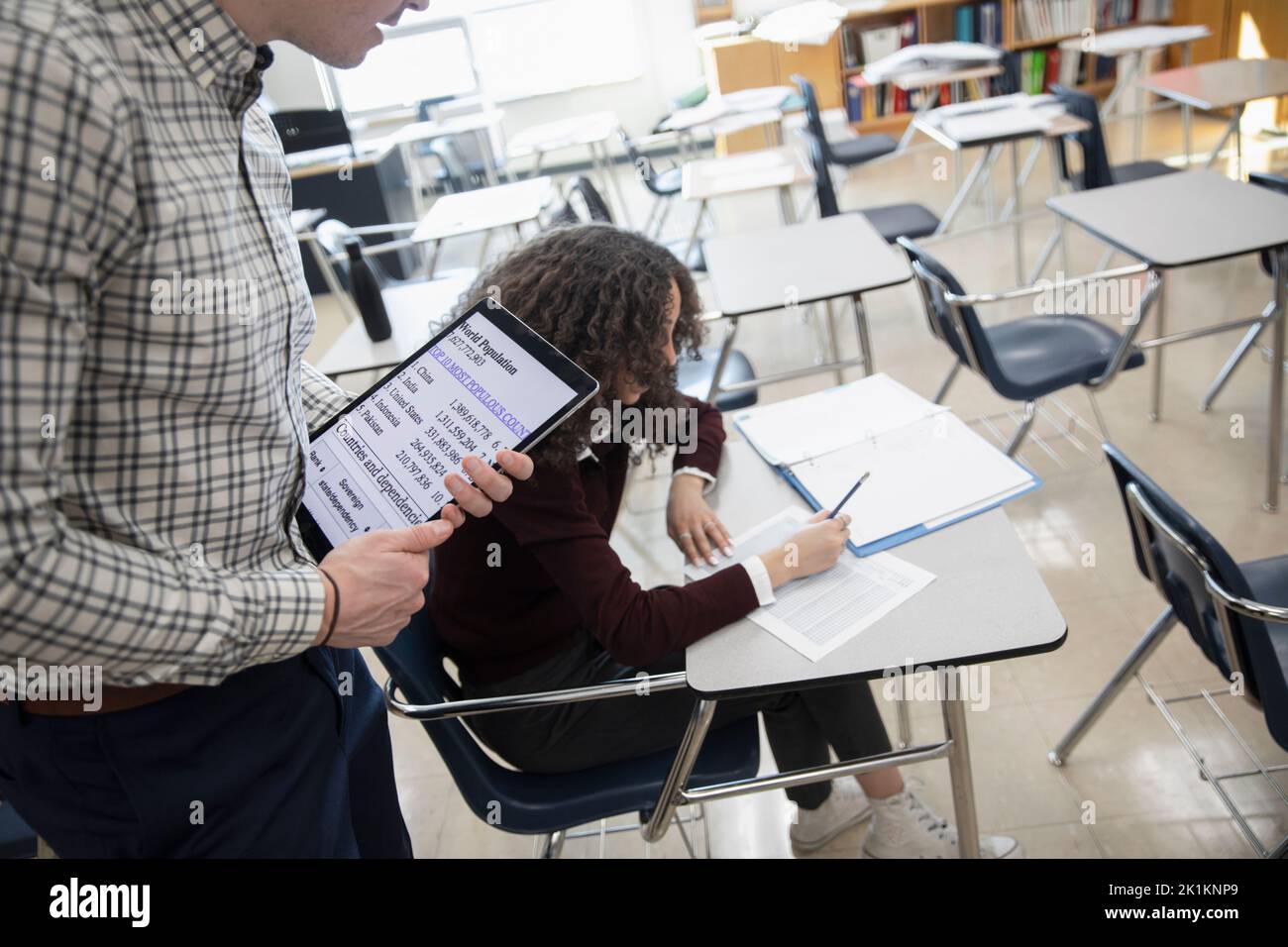 High school geography teacher helping student in classroom Stock Photo