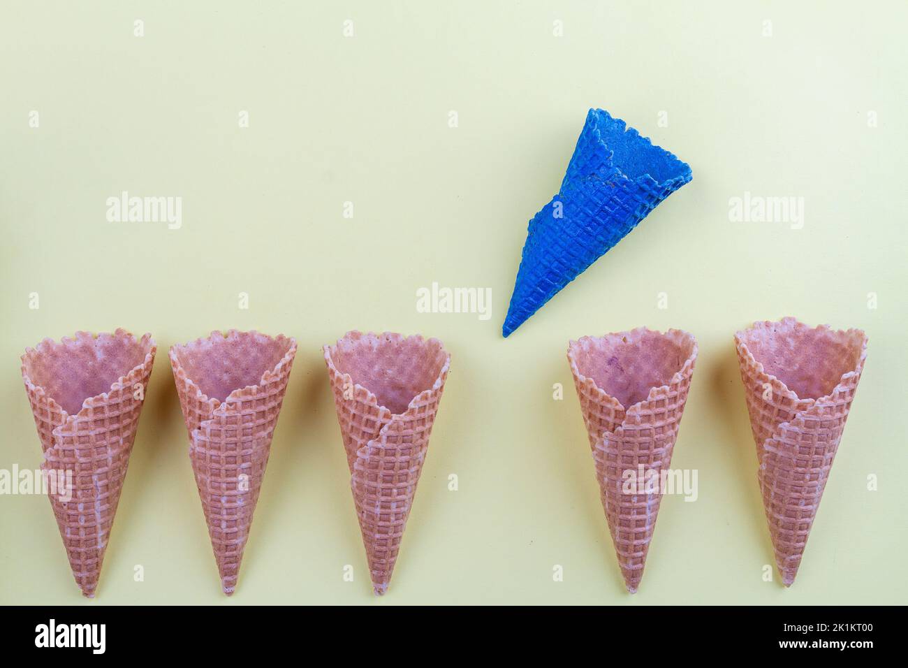 Blue ice cream cone waffle between ordinary ones. Stand out from others concept. Stock Photo