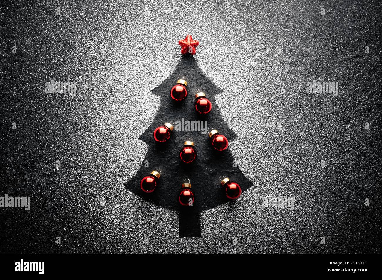 Decorated Christmas tree with red christmas balls and star on top created from artificial snow on black background. Winter holidays concept Stock Photo