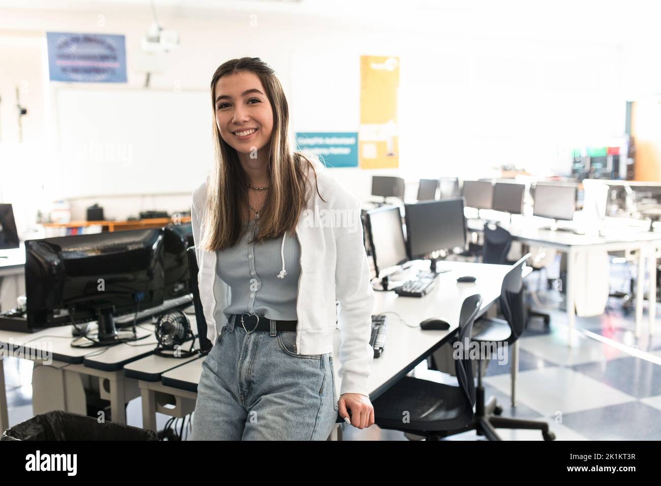 Portrait happy high school girl student in computer lab after school